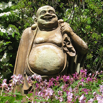 Smiling Buddha statue in a landscaped bed