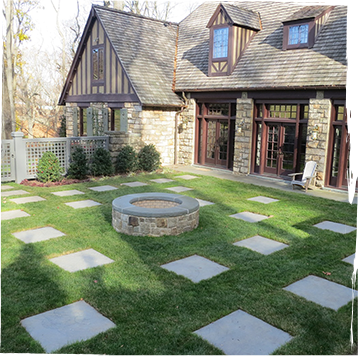 Stone firepit with randomly placed bluestone pavers in a backyard