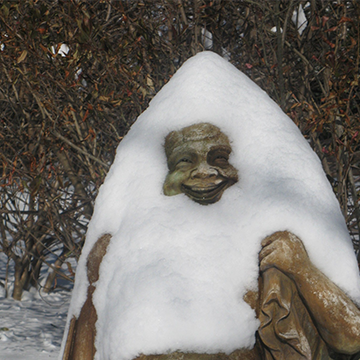 Snow piled on top of a smiling Buddha statue